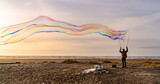 Fototapeta Tęcza - Sunlight refracting through Large colorful bubbles on the ocean coast during sunset.
