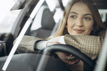 Wall Mural - Beautiful woman sitting in car in a car showroom