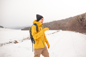 Wall Mural - The man dresssed yellow warm jacket and trousers, bagpack traveling in the snow landscape