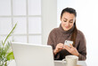 © Retamosa - a woman working at the computer and looking at the messages on the phone from the office
