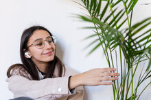 Content Woman In Earphones Touching Plant