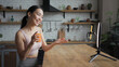© RZ Images - Healthy Asian woman live streaming on smartphone and holding fresh juice in her hands. Product placement concept