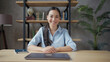 © RZ Images - Young asian woman teacher sitting at the table, looking at camera and smiling