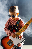 Fototapeta Storczyk - Dziecko gra na gitarze elektrycznej - rockowy chłopiec w studiu - zespół muzyczny - mały muzyk