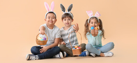 Wall Mural - Little children with Easter eggs and bunny ears on beige background