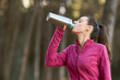 eco friendly woman drinking water in recyclable aluminum bottle in the forest