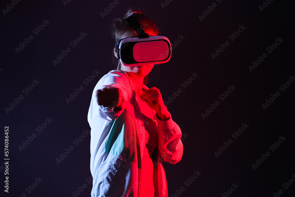 Pretty young woman in VR glasses training on black background