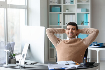 Wall Mural - Young accountant sitting at table in office