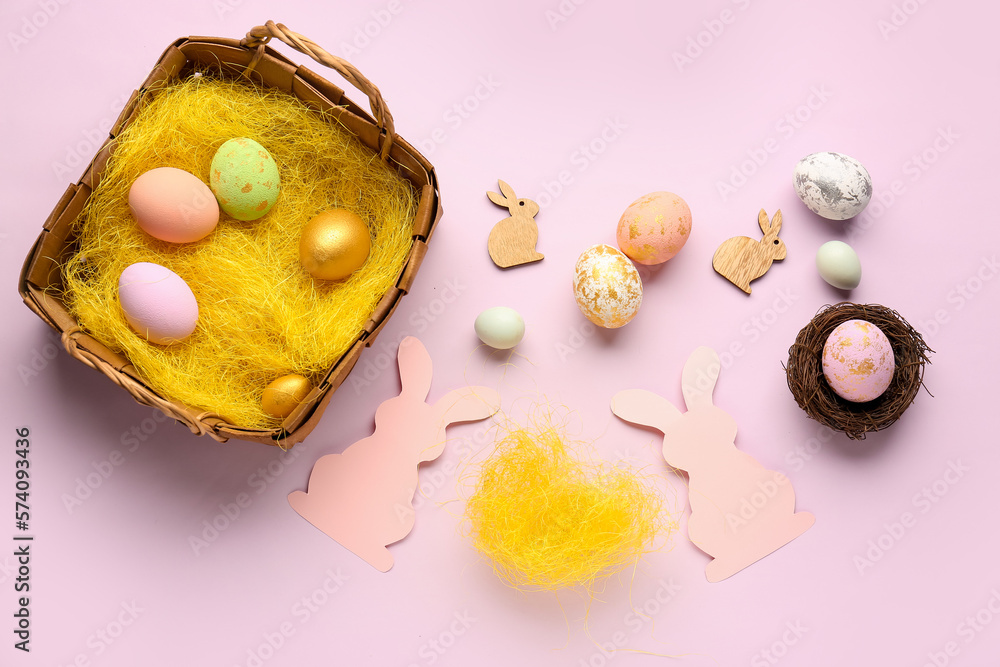 Paper rabbits and basket with Easter eggs on pink background