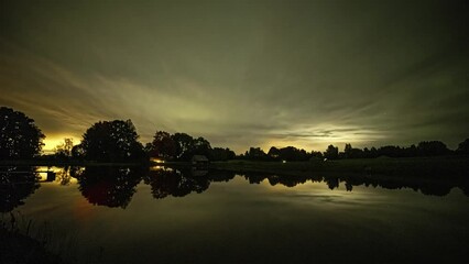 Poster - cloudy sunset on a lake with a cottage time lapse. green meadow in the countryside with a lake. a da