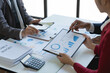 © Phimwilai - Group of Asian business people meeting new startup project pointing discussion graph and data analysis charts and graphs business finance inside office accounting concept management renew.