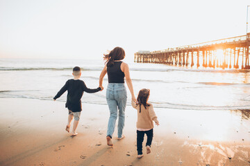 mom and kids running on the beach in low tide