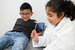 © Arlette - Latino girl and boy play to be a doctor with a white coat that is too big for her and patient who acts to feel sick very entertaining and funny they make jokes