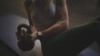 Close-up portrait of an unrecognized woman wearing sports bra doing kettelbell russian twist on the floor at gym. Shot in slow-motion