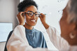 © Clement C/peopleimages.com - Glasses check, black woman and customer with store worker and optician looking at lense. Eye consulting, smile and eyewear assessment in a frame shop for vision test and prescription exam for eyes