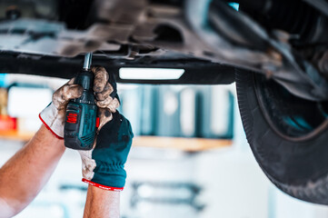 Wall Mural - Mechanic working on a vehicle in a car service. inspection of the car by a mechanic of the chassis of the car. Repair default