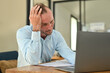© Prathankarnpap - Stressed caucasian man office worker sitting at desk, feeling distressed anxious with work deadline