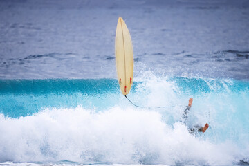 Professional surfer falling from ocean waves On banzai pipeline north shore Oahu Hawaii. Surfing wipe out a large sea wave on short surfboard in the summer sun.