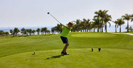 Wall Mural - Golfer on a golf course, ready to tee off. Golfer with golf club hitting the ball for the perfect shot.