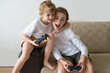 © Chiralli - Excited children playing video games PS5 XBOX controller console two kids friends expressing emotions while enjoying their hobby playstation joystick