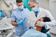 © Drazen - Male dentist examining teeth of African American woman at dental clinic.