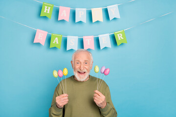 Sticker - Portrait of attractive cheerful funky crazy grey-haired man holding eggs festal occasion isolated over bright blue color background