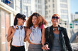 Women friends, holding hands and walk in city with smile, support or happiness for summer travel together. Black woman students, laughing and comic joke with excited face, happy and group vacation
