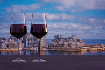 Glass of two red wine with view of Sliema harbor and skyscrapers in Malta. View from Valletta.