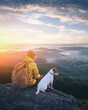© Ivan Kmit - Alone tourist sitting on the edge of the cliff with dog against the backdrop of an incredible mountain landscape. Sunny day and blue sky
