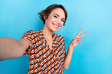 Poster - Photo of lovely cheerful person make selfie toothy smile demonstrate v-sign isolated on blue color background