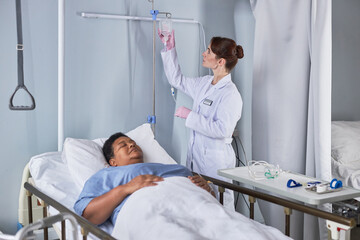 Wall Mural - Portrait of young nurse setting up IV therapy for senior woman in hospital bed