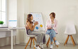 Therapeutic psychological session for teenagers. Teenage girl is talking to female psychotherapist while sitting in doctor's office. Psychologist with clipboard advises child. Web banner.