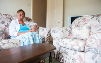 Retirement: Home Alone. A solitary senior lady sitting looking in contemplation at the world outside her window. From a series of related images.