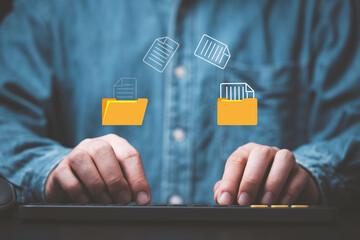 Businessman hand using laptop computer with data folder file icon for information exchange and transfer concept.