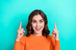 Photo of young funny overjoyed brown curly hair lady wear orange shirt surprised directing fingers up mockup isolated on aquamarine color background