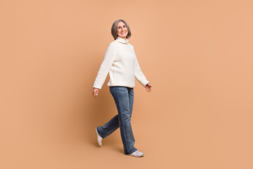 Poster - Full length photo of funny charming woman wear knitted pullover walking empty space isolated beige color background