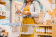 © nataliaderiabina - Woman with metal basket buying personal hygiene items in zero waste shop. Female choosing eco-friendly vegan cosmetics products in sustainable plastic free store.