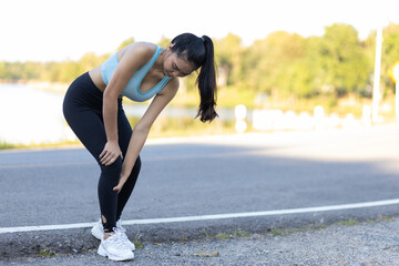 The female athlete suffered an ankle injury. A female runner has pain in her ankle. A runner sits down with a knee injury. The female athlete fell and had a bruise on her knee.