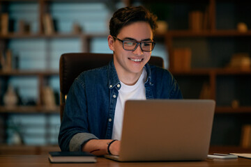 Cheerful young guy working at office late at night