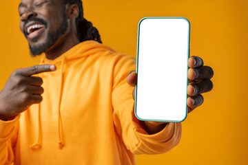 Smiling african man pointing at cellphone with blank screen with copy space