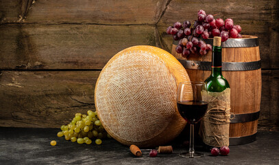 Wall Mural - Glass of red wine, cheeses and grapes on a wooden background, A head of hard cheese, Long banner format