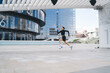 © BullRun - Focused sportive woman running along urban buildings