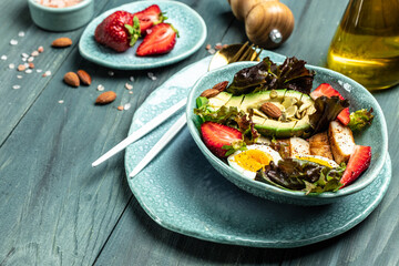 Poster - Ketogenic low carbs diet, Plate with keto foods: two eggs, avocado, grilled chicken fillet, nuts, strawberries and fresh salad. Healthy fats, clean eating for weight loss. top view