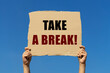 © Tepsarit - Take a break text on box paper held by 2 hands with isolated blue sky background. This message board can be used as business concept to inform everyone to take a break.