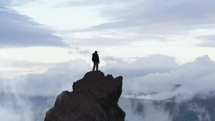 Adventurous Man Hiker standing on top of peak with rocky mountain in background. Adventure Composite. 3d Rendering rocks. Aerial Image of landscape from Yukon, Canada. Sunset Sky. 3D Illustration