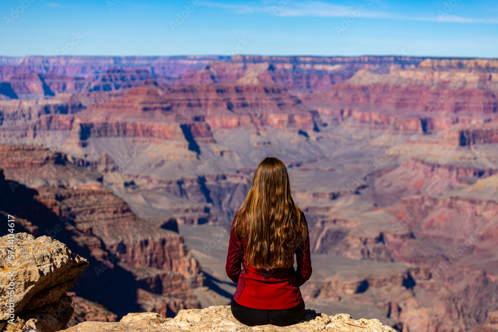 long haired hiker girl sitting on the edge of grand canyon; hiking in ...