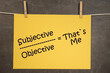 napis subjective/objective=that`s me na wiszącej żółtej kartce na ciemnym tle