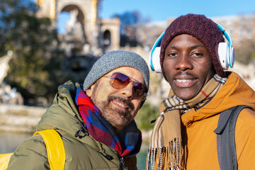 Two happy friends looking at camera in winter clothes on vacation in the city.