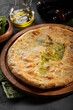Khachapuri with spinach and cheese on wooden plate and green napkin