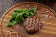 Grilled steak on wooden chopping board with spinach and spices